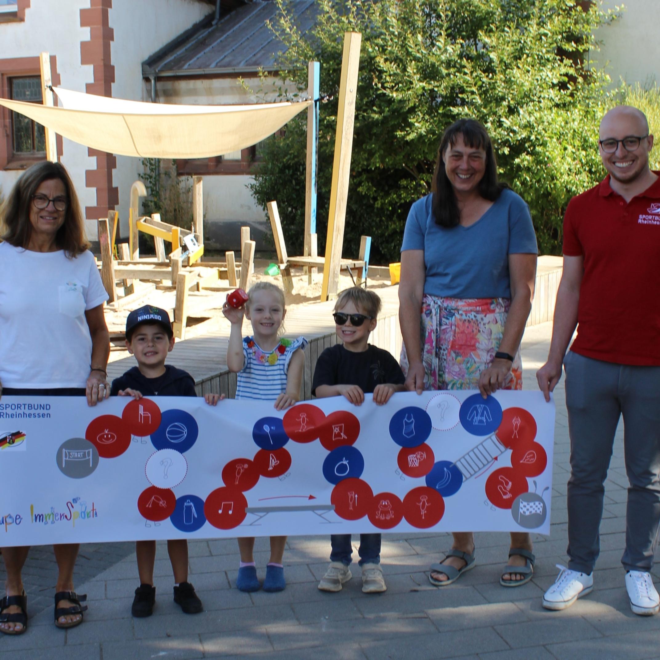 Sportbund Rheinhessen Geschäftsstellenleiter Alexander Beuerle (r.) übergibt die Raupe ImmerSport an den Kindergarten Herz Jesu in Mainz-Mombach